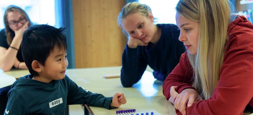 Ung elev som veiledes av to folkehøgskoleelever - Klikk for stort bilde